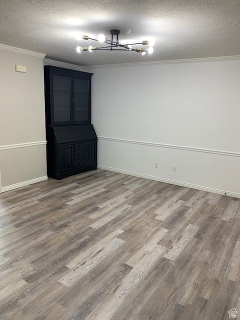 Spare room with ornamental molding, a textured ceiling, wood finished floors, and baseboards