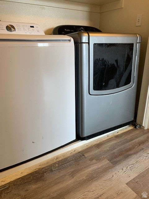 Laundry area with wood finished floors and washer and clothes dryer