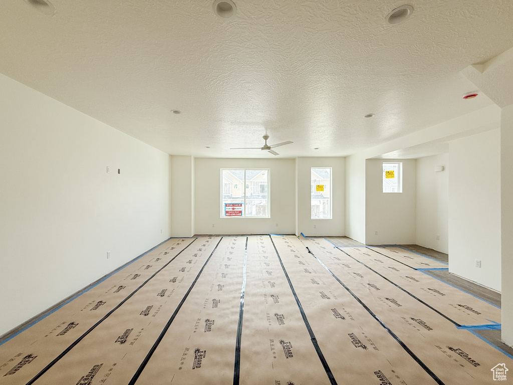 Empty room featuring plenty of natural light, ceiling fan, and a textured ceiling