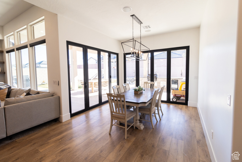 Dining space with a notable chandelier, dark wood-type flooring, french doors, and a healthy amount of sunlight