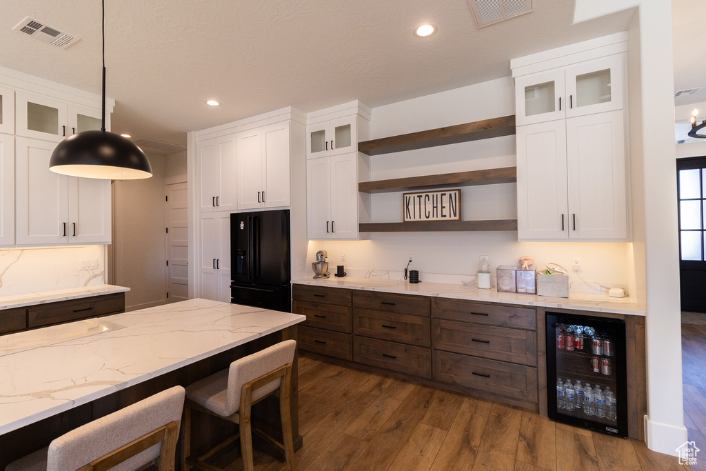 Kitchen featuring white cabinetry, beverage cooler, and decorative light fixtures