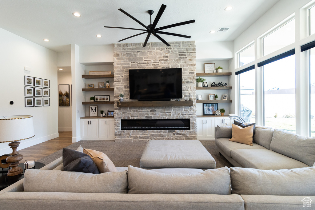 Living room with plenty of natural light, hardwood / wood-style floors, a stone fireplace, and built in shelves