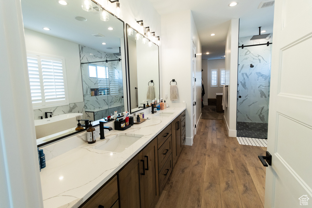 Bathroom featuring vanity, a wealth of natural light, independent shower and bath, and wood-type flooring