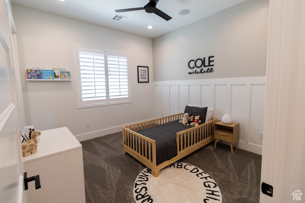 Carpeted bedroom with ceiling fan and a crib