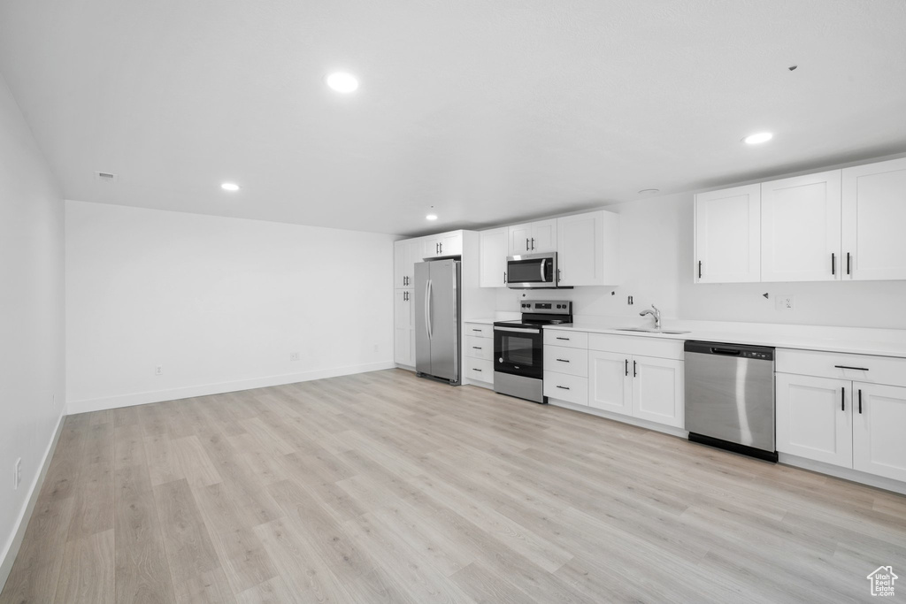 Kitchen featuring white cabinetry, appliances with stainless steel finishes, sink, and light hardwood / wood-style flooring