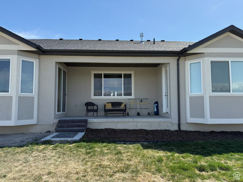 Rear view of property with a yard, covered porch, and stucco siding