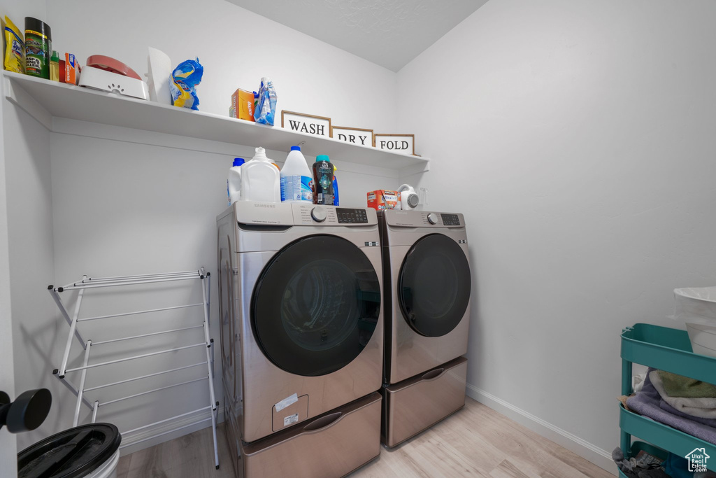 Washroom featuring washer and clothes dryer and light wood-type flooring