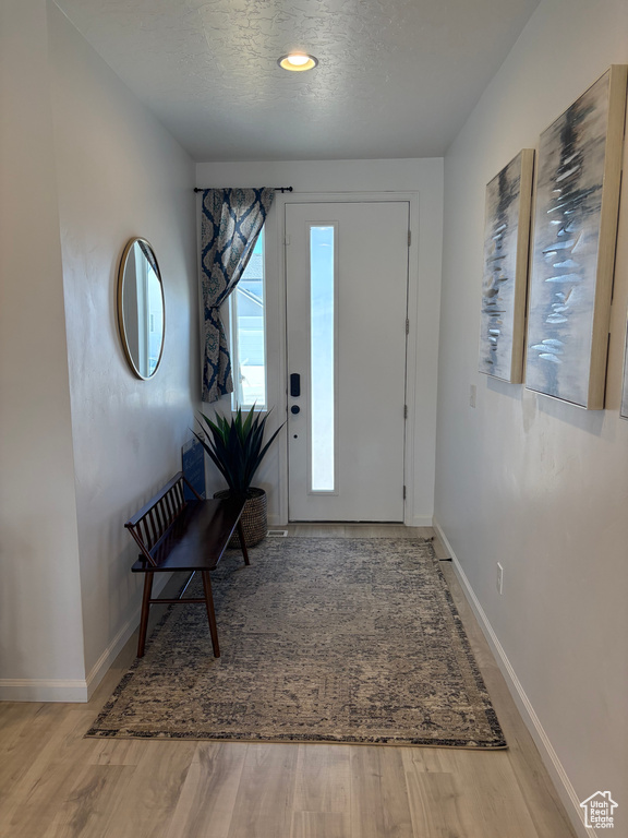 Entryway with baseboards, a textured ceiling, and light wood finished floors