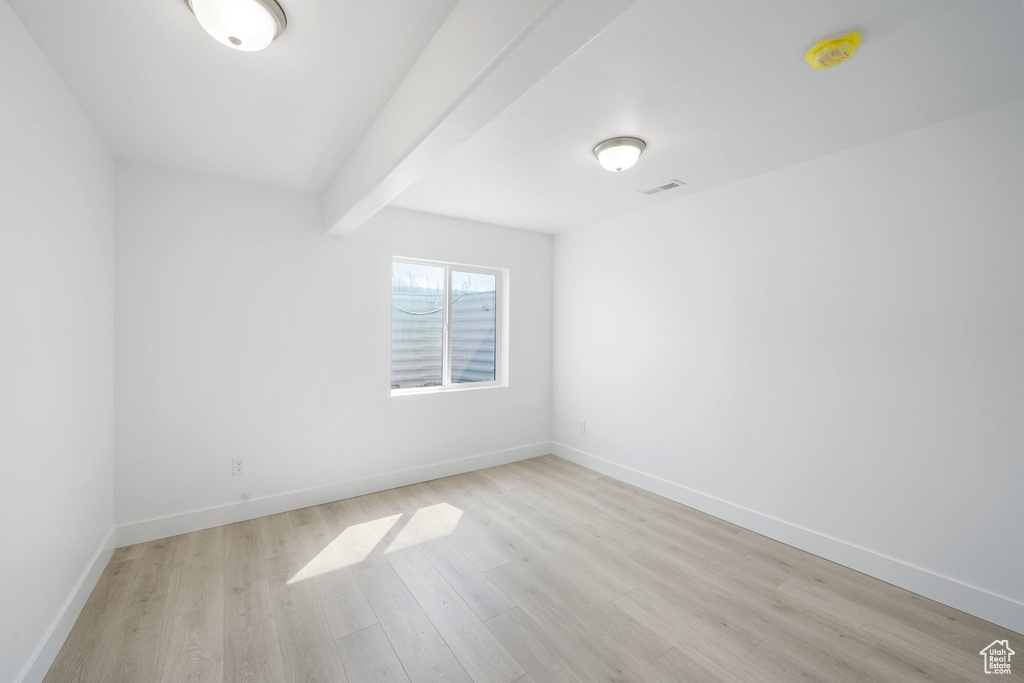 Spare room with beam ceiling and light hardwood / wood-style flooring