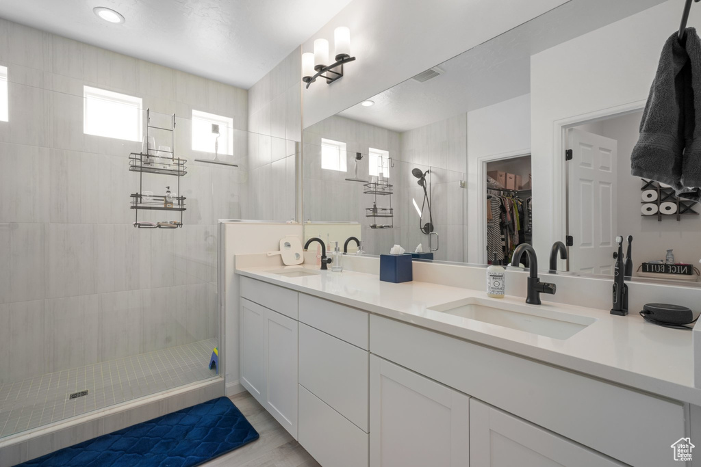 Bathroom with hardwood / wood-style flooring, tiled shower, a healthy amount of sunlight, and vanity