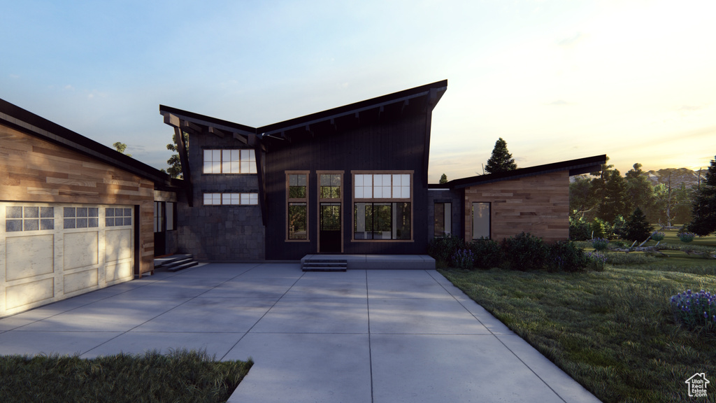 Back house at dusk featuring a lawn and a patio area