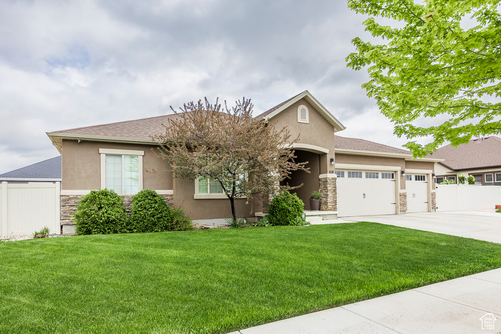 Single story home featuring stone siding, stucco siding, an attached garage, and driveway