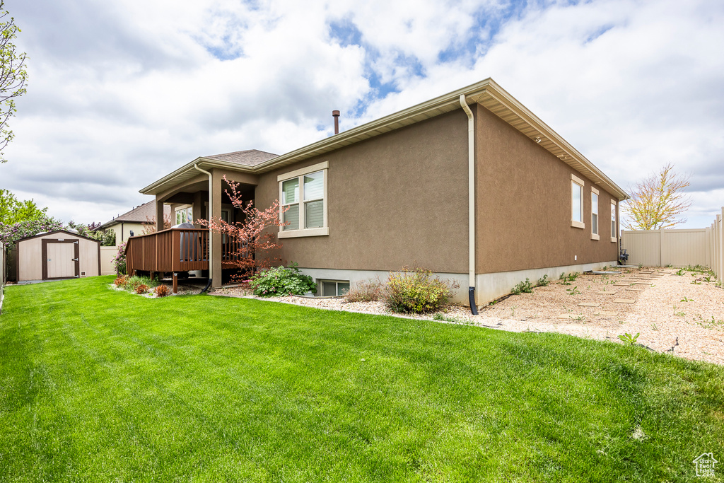 Back of property with a shed, an outdoor structure, a deck, and stucco siding