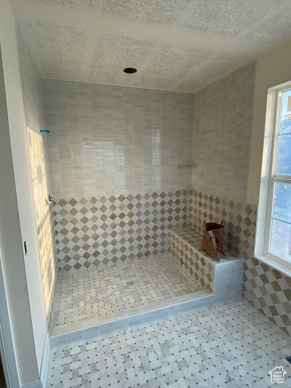 Bathroom with a textured ceiling and tiled shower