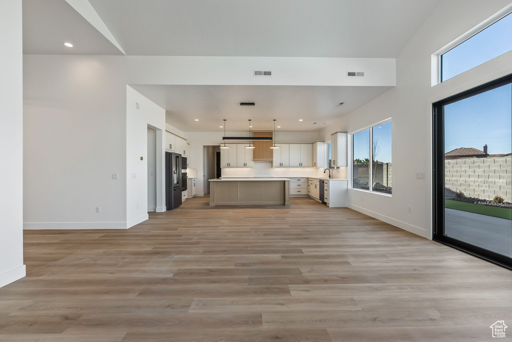 Kitchen with light wood-type flooring, hanging light fixtures, a wealth of natural light, and a kitchen island