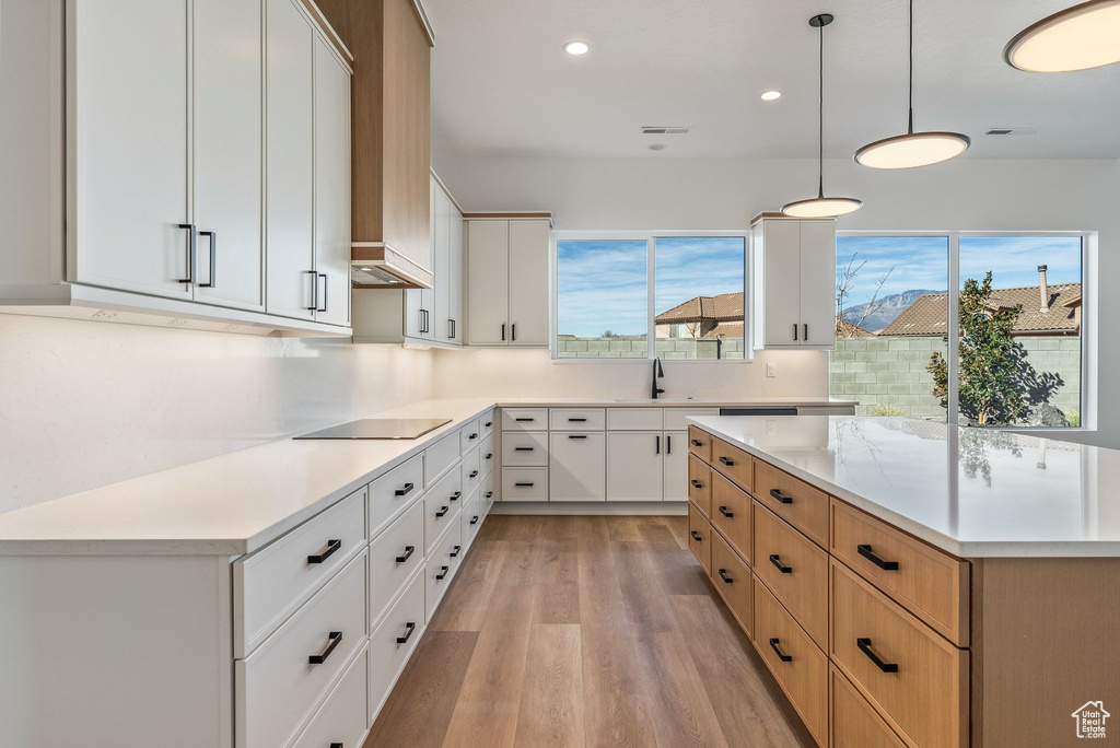 Kitchen with white cabinetry, sink, pendant lighting, and black electric cooktop
