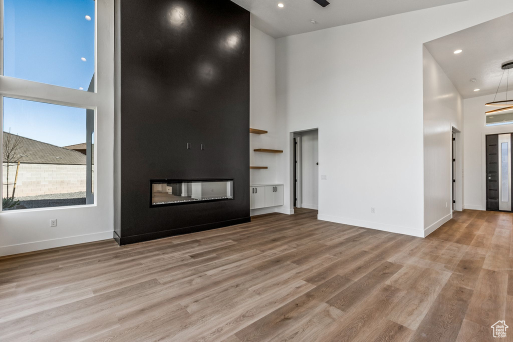 Unfurnished living room with a high ceiling, a fireplace, and light hardwood / wood-style floors