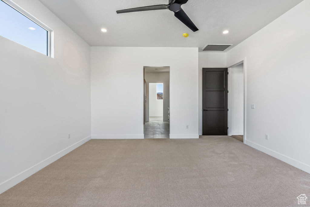 Unfurnished bedroom with ceiling fan and light colored carpet