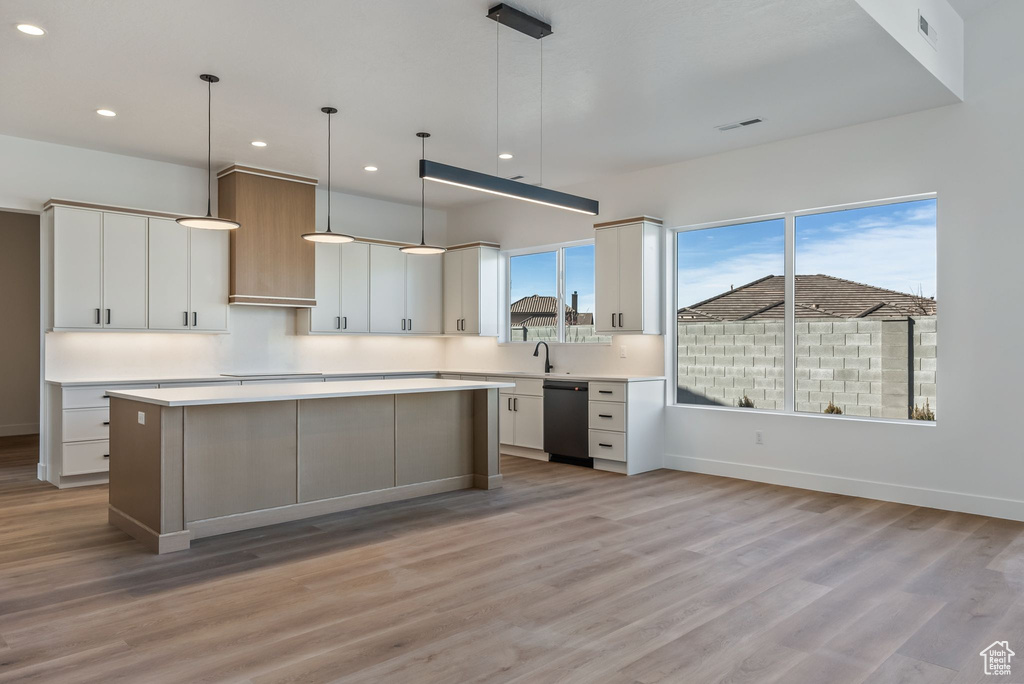 Kitchen with hanging light fixtures, dishwasher, white cabinets, and a kitchen island