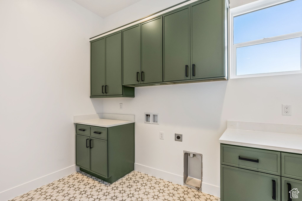Washroom with hookup for a washing machine, cabinets, and hookup for an electric dryer