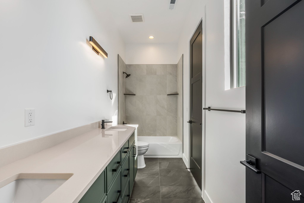 Full bathroom with vanity, tiled shower / bath combo, and toilet