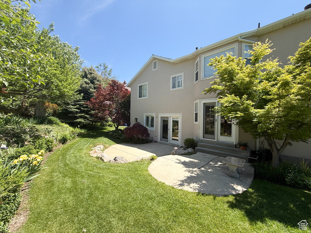 Rear view of house with stucco siding, a patio area, a yard, and french doors