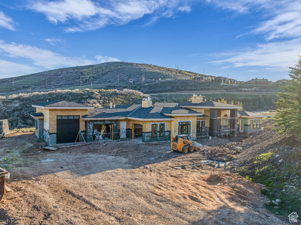 Rear view of house with a chimney, an attached garage, a mountain view, and french doors