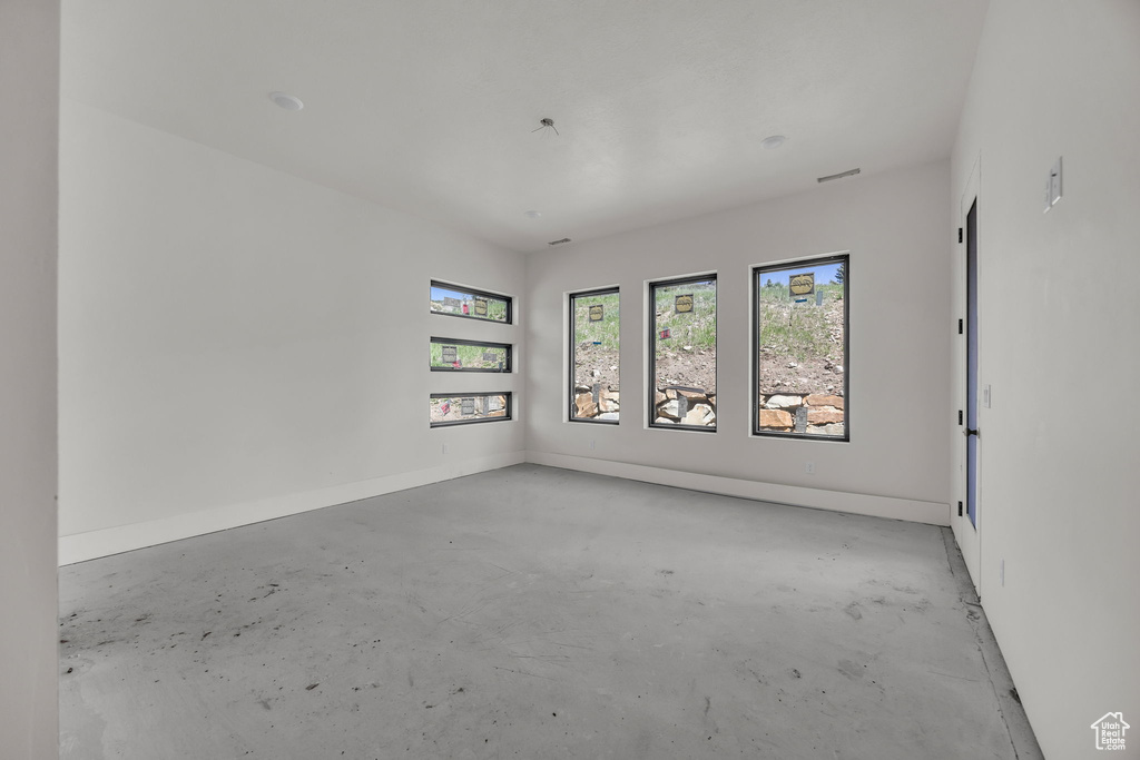 Spare room featuring concrete flooring and baseboards