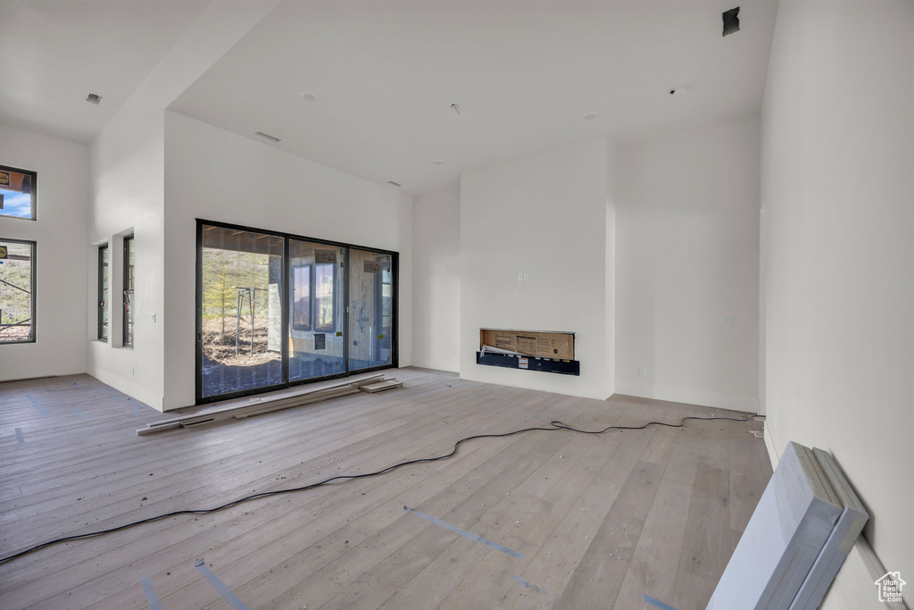 Unfurnished living room featuring hardwood / wood-style flooring and a towering ceiling