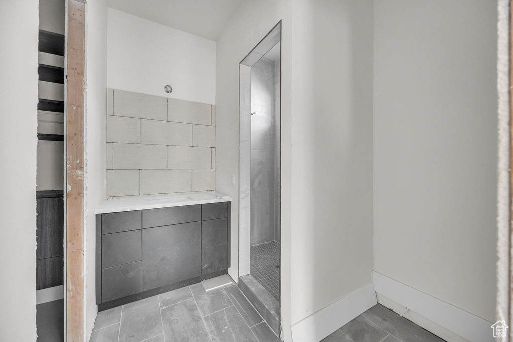 Full bathroom with a tile shower and baseboards