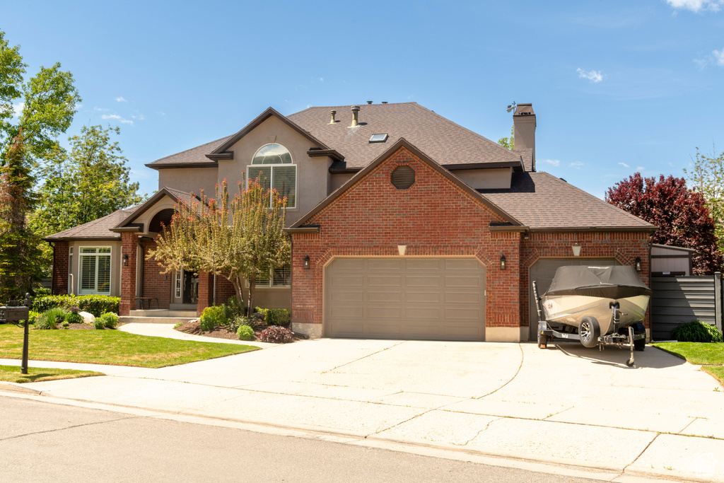 Traditional-style home with concrete driveway, brick siding, a garage, and a chimney