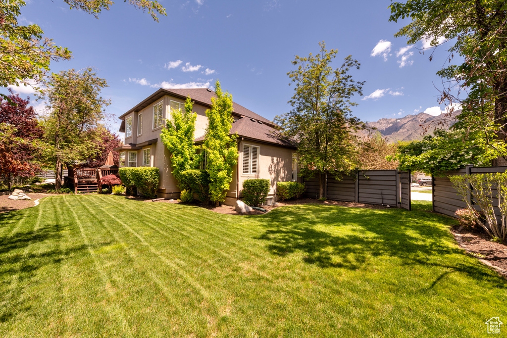 View of grassy yard with a deck with mountain view