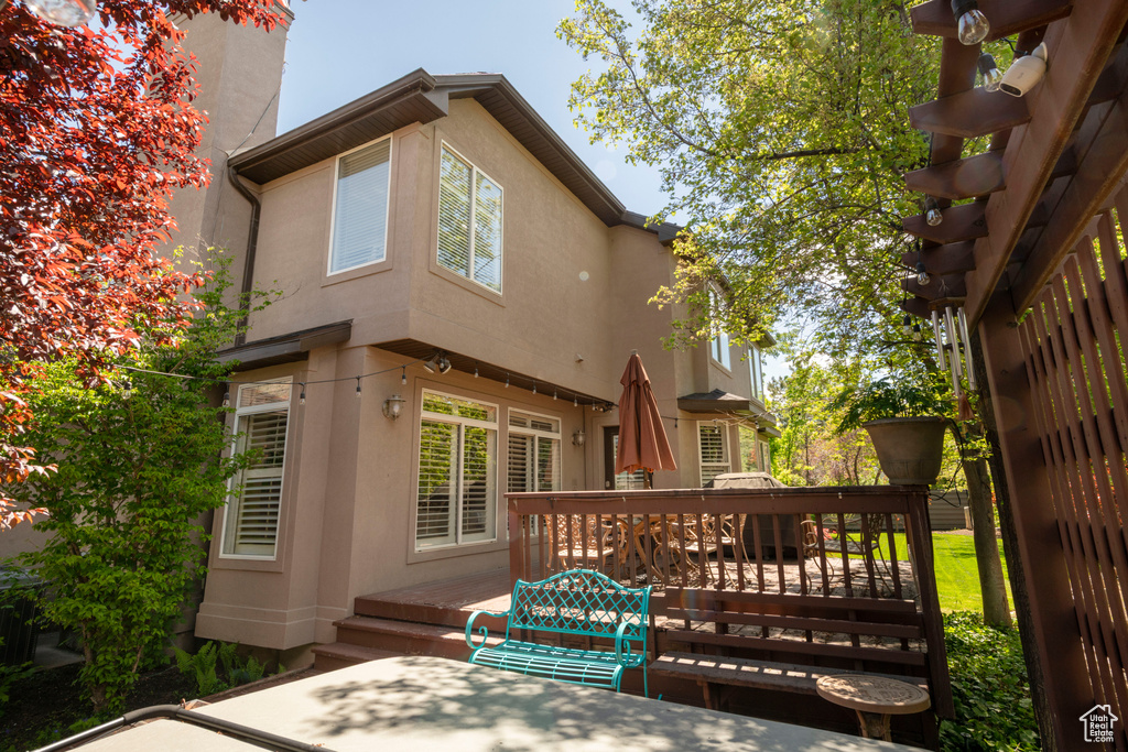 Rear view of house with stucco siding and a wooden deck