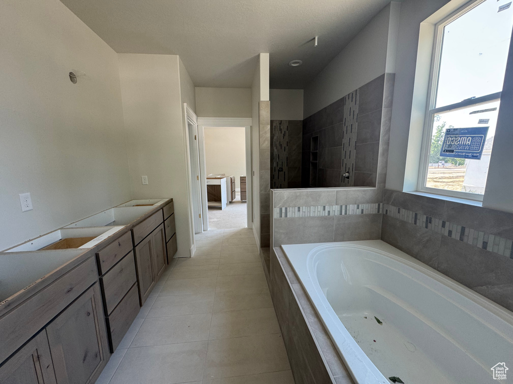 Full bath featuring a garden tub, tile patterned floors, and double vanity