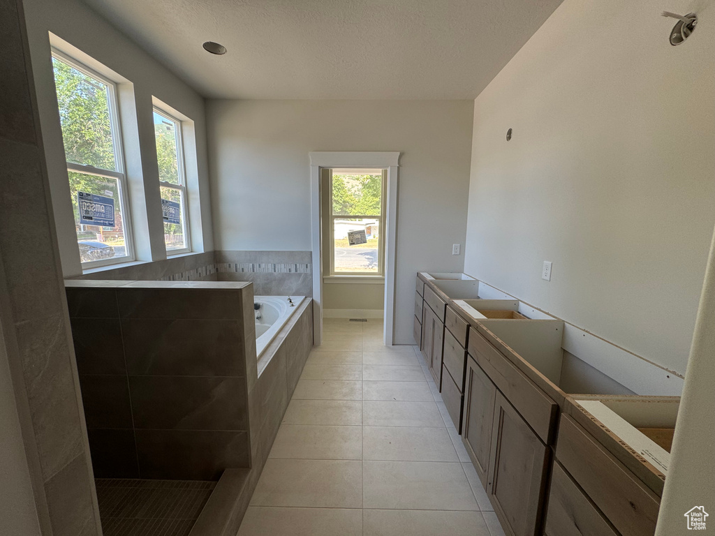 Bathroom with a bath, tile patterned floors, and a textured ceiling