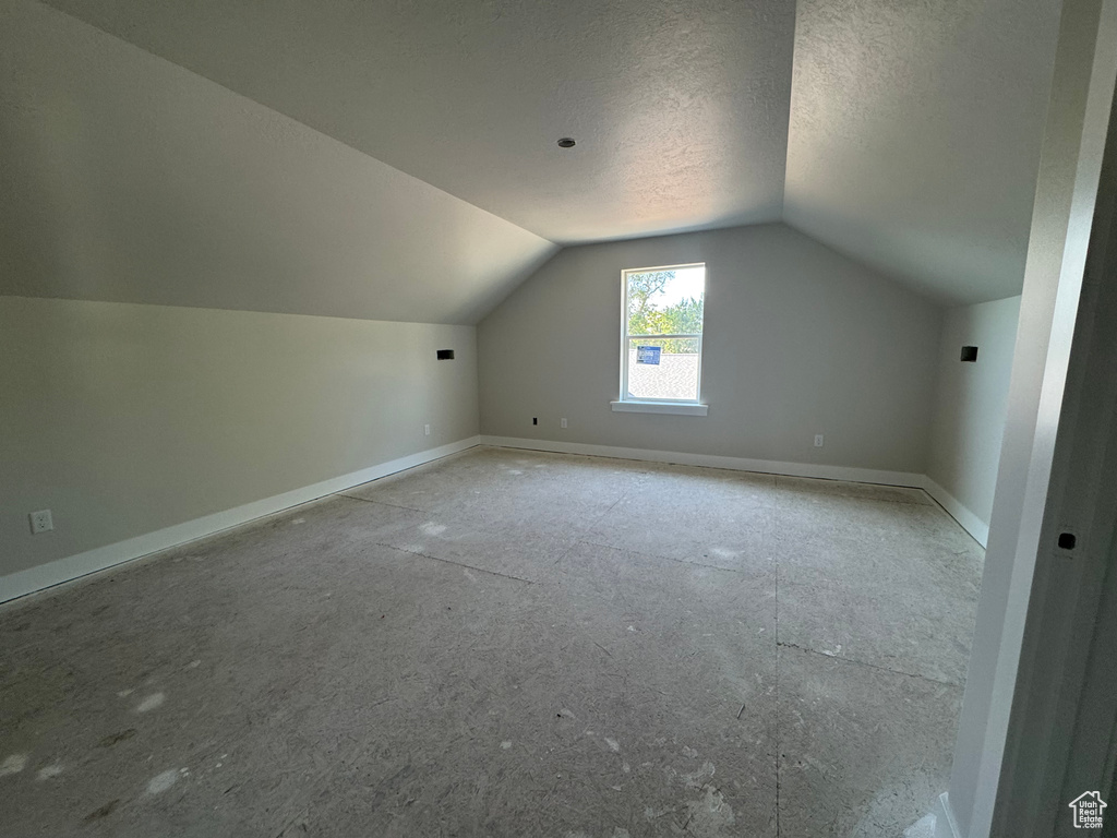 Additional living space featuring lofted ceiling and a textured ceiling