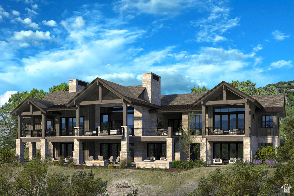 Rear view of property featuring stone siding, a chimney, and a standing seam roof