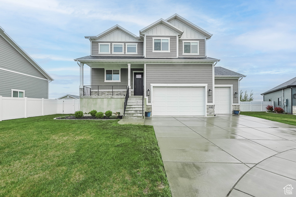 Craftsman house featuring board and batten siding, covered porch, driveway, a garage, and stone siding