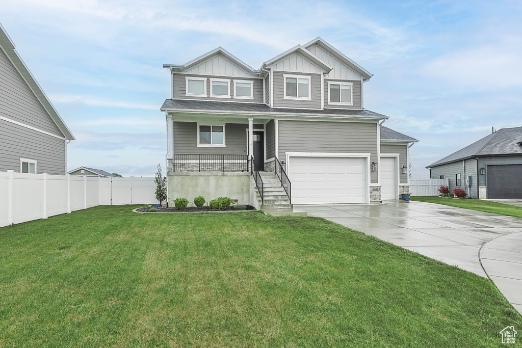 Craftsman-style home with board and batten siding, covered porch, driveway, an attached garage, and stairs