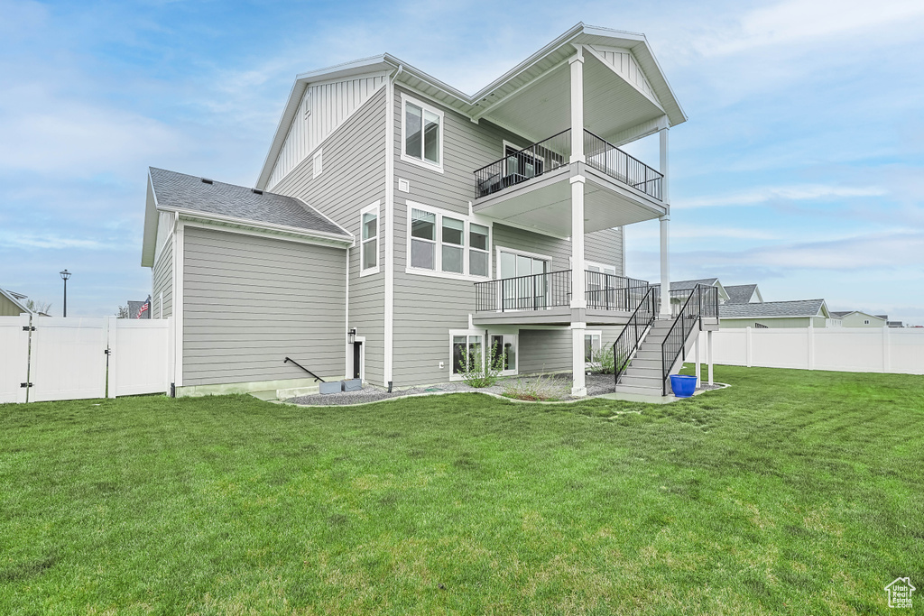 Rear view of house with a balcony, stairway, a gate, and board and batten siding