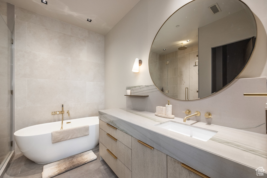 Bathroom with tile walls, a shower stall, a freestanding bath, and vanity