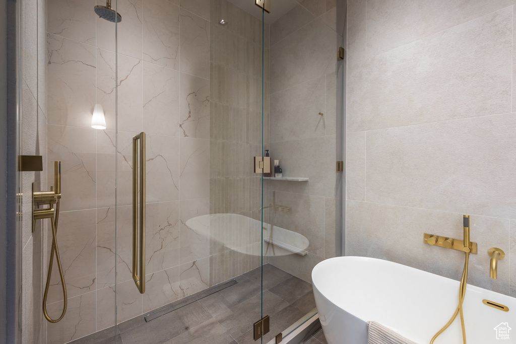 Full bathroom featuring tile walls, a shower stall, and a freestanding bath