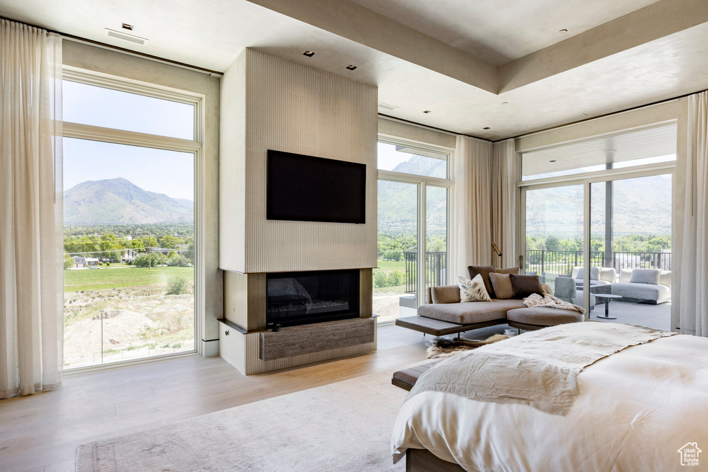 Bedroom with access to exterior, wood finished floors, and a large fireplace