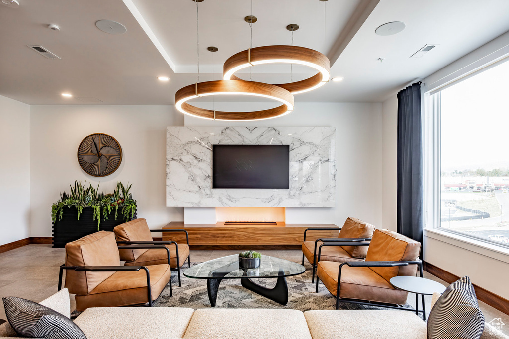 Living room with baseboards, a raised ceiling, and recessed lighting