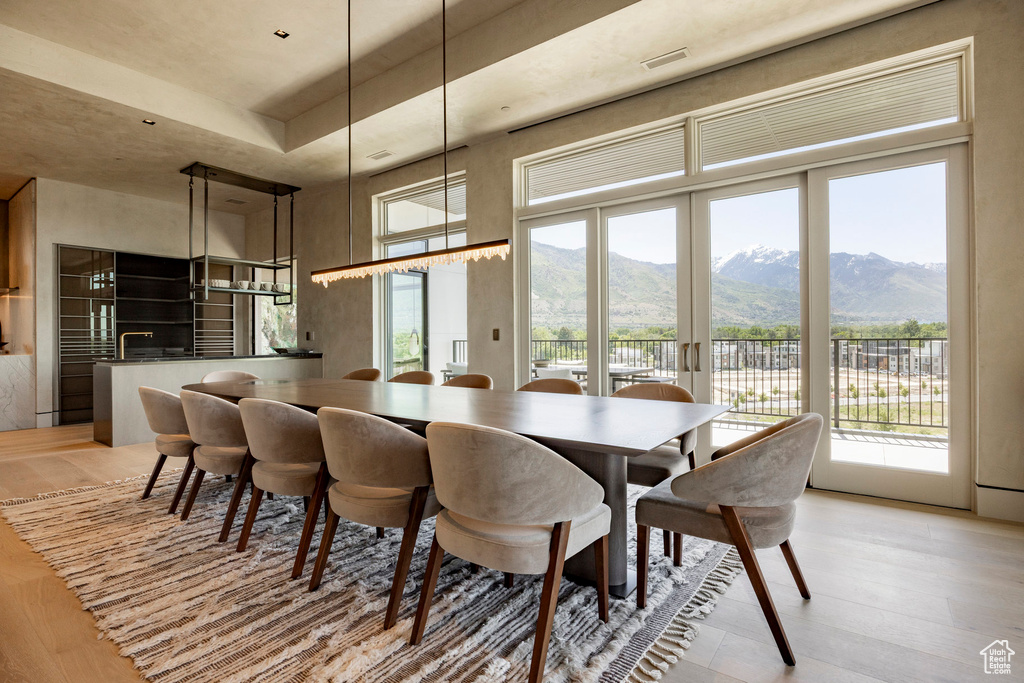 Dining space with light wood-type flooring, a mountain view, plenty of natural light, and a high ceiling