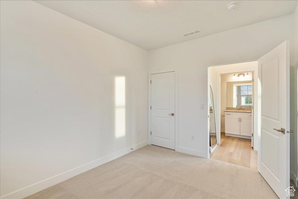 Unfurnished bedroom featuring sink and light colored carpet