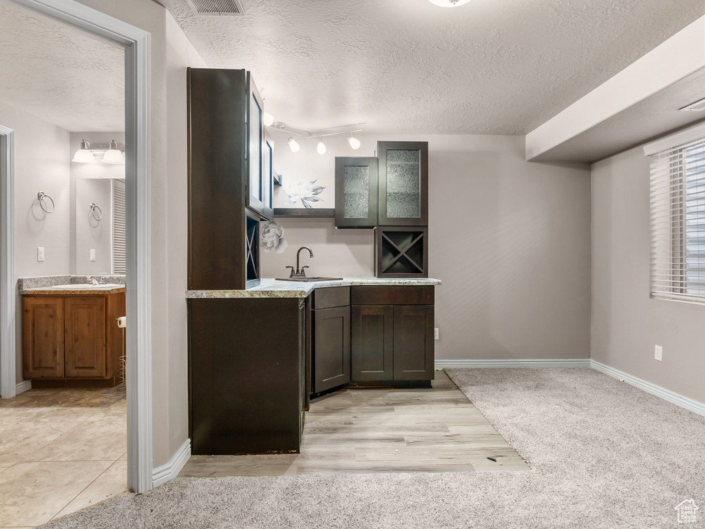 Kitchen featuring dark brown cabinetry, sink, and a textured ceiling