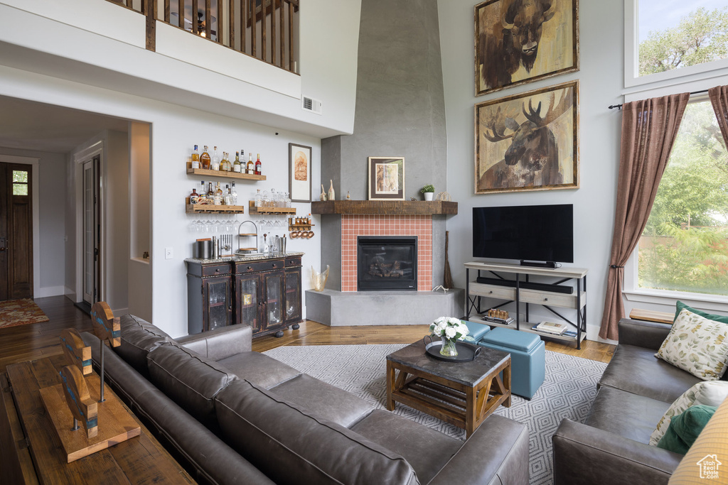 Living area featuring baseboards, a high ceiling, wood finished floors, and visible vents