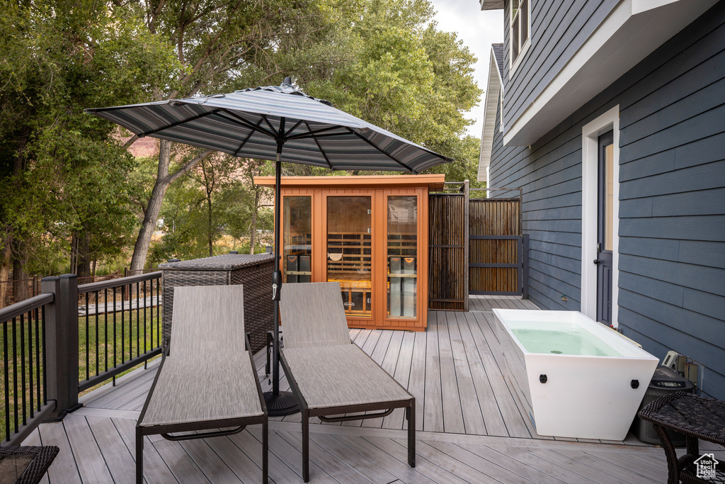 Wooden deck with an outdoor hot tub, fence, and outdoor dining area