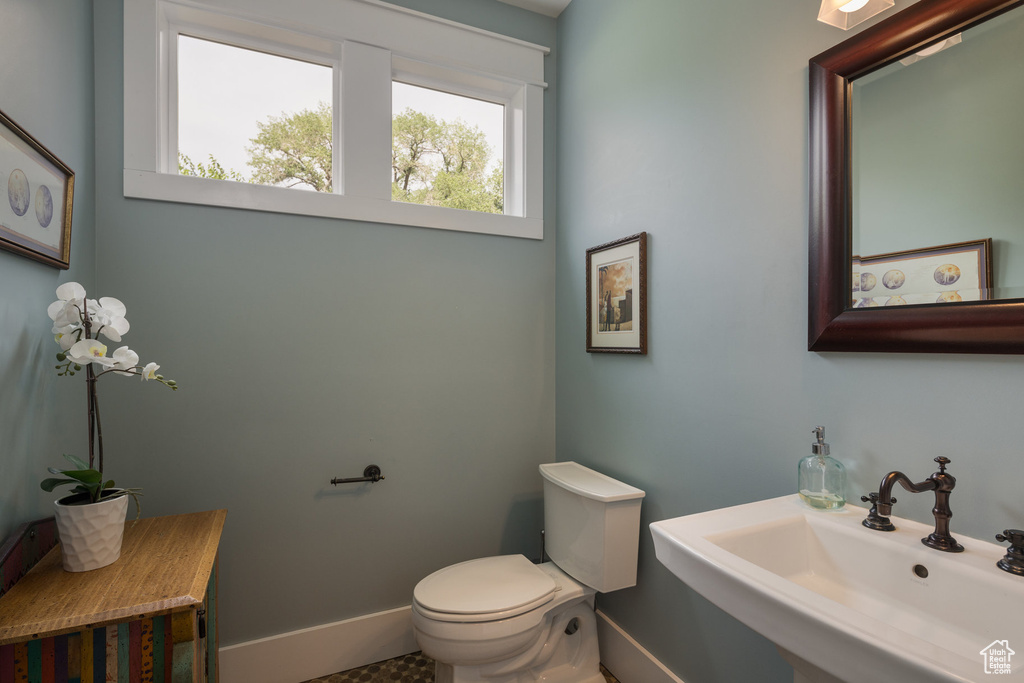 Half bath with baseboards, a sink, and toilet